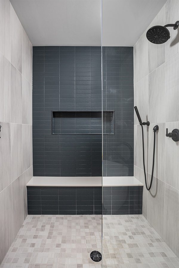 the textured surface of the matte blue shower tile pairs with the matte black plumbing fixtures to create a spa-like getaway in this mid century modern bath in the heart of the city.