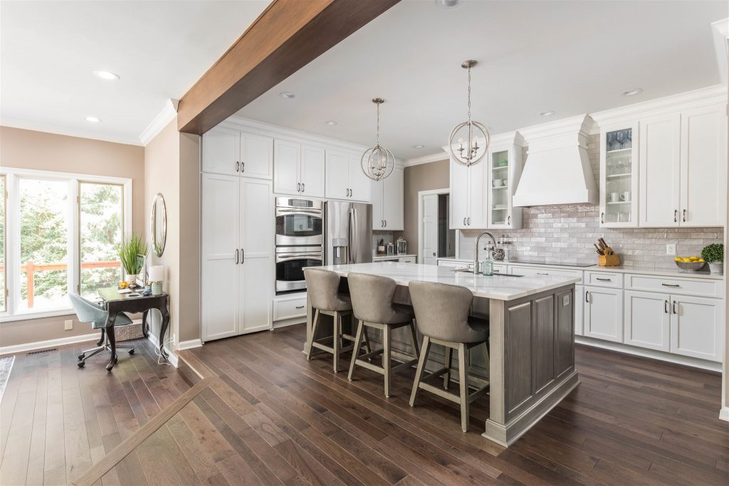 the back of this kitchen island has room for added seating and a flexible layout that invites conversation between the kitchen and living room