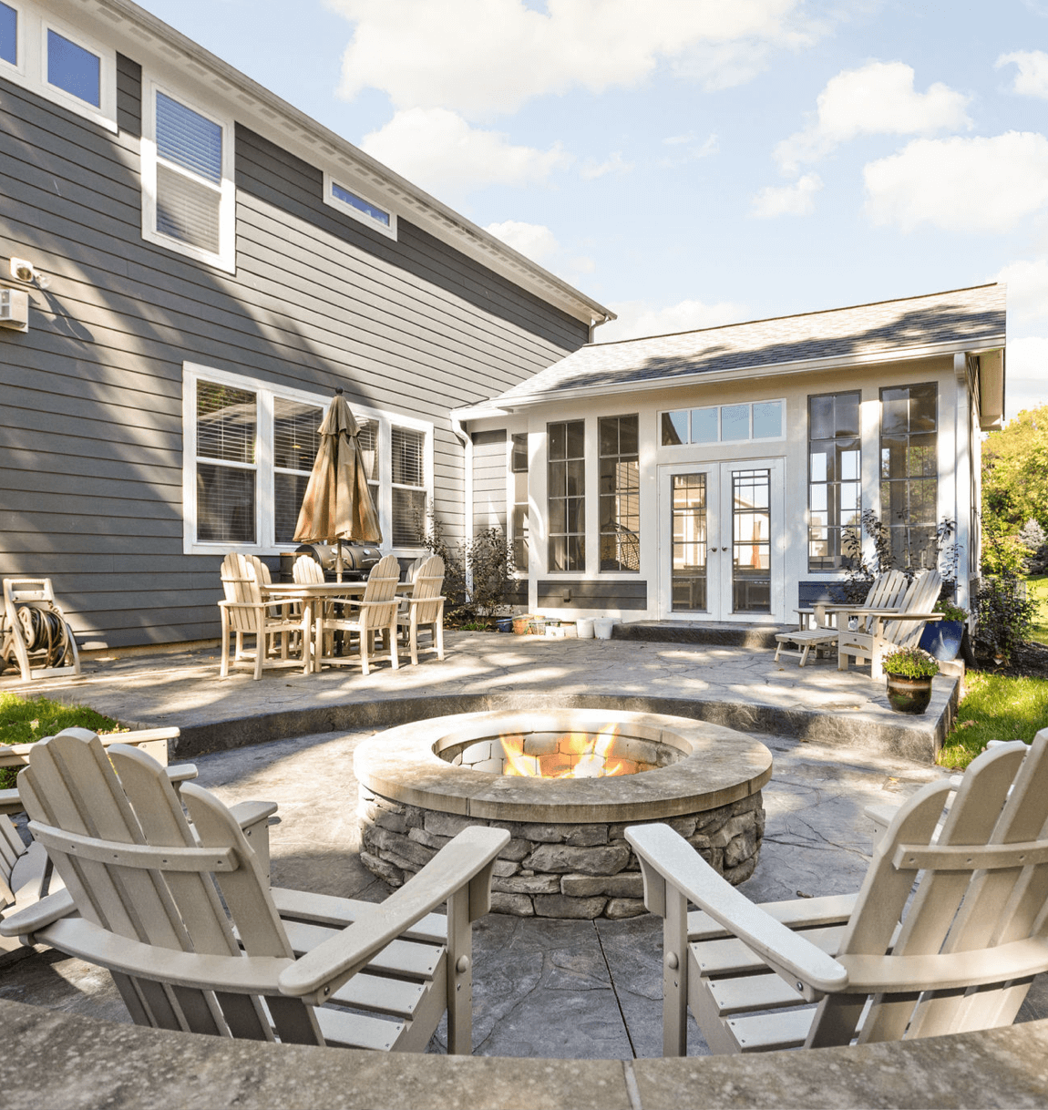 Backyard patio with a stone fire pit and a glass-enclosed addition