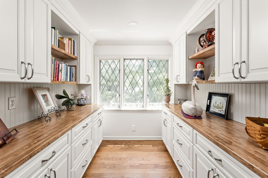 bulters pantry with wood countertops and white cabinetry