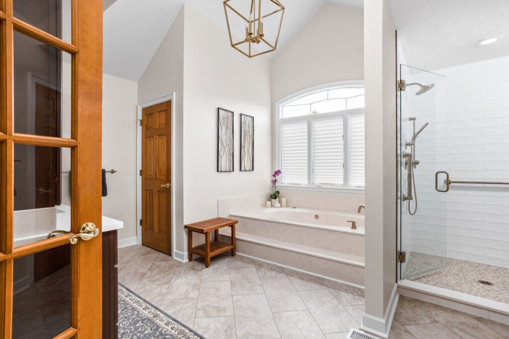 A Carmel, IN Bathroom Renovation picture showing a water closet, built in soaking tub and walk in shower. Light naturally tones.
