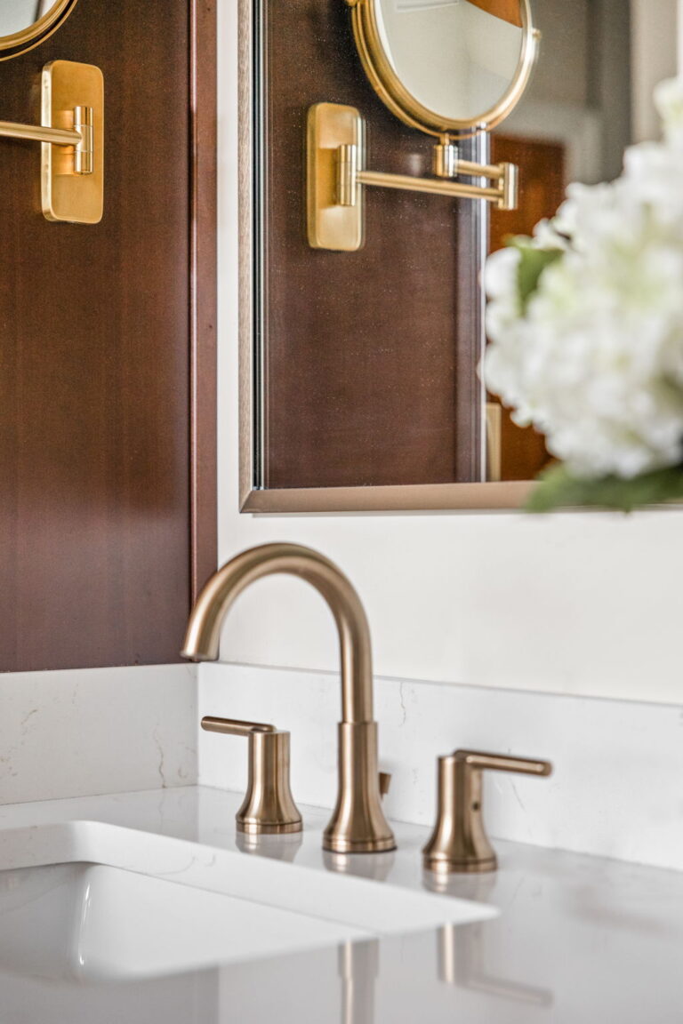 A Carmel, IN Bathroom Renovation picture showing a matte brass sink faucet with white countertops.