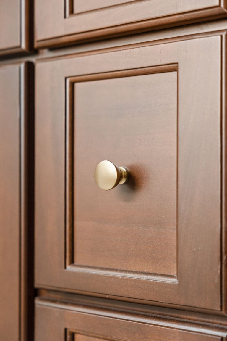 A Carmel, IN Bathroom Renovation picture showing the detail of the rich wood stained drawer with matte brass knob hardware.