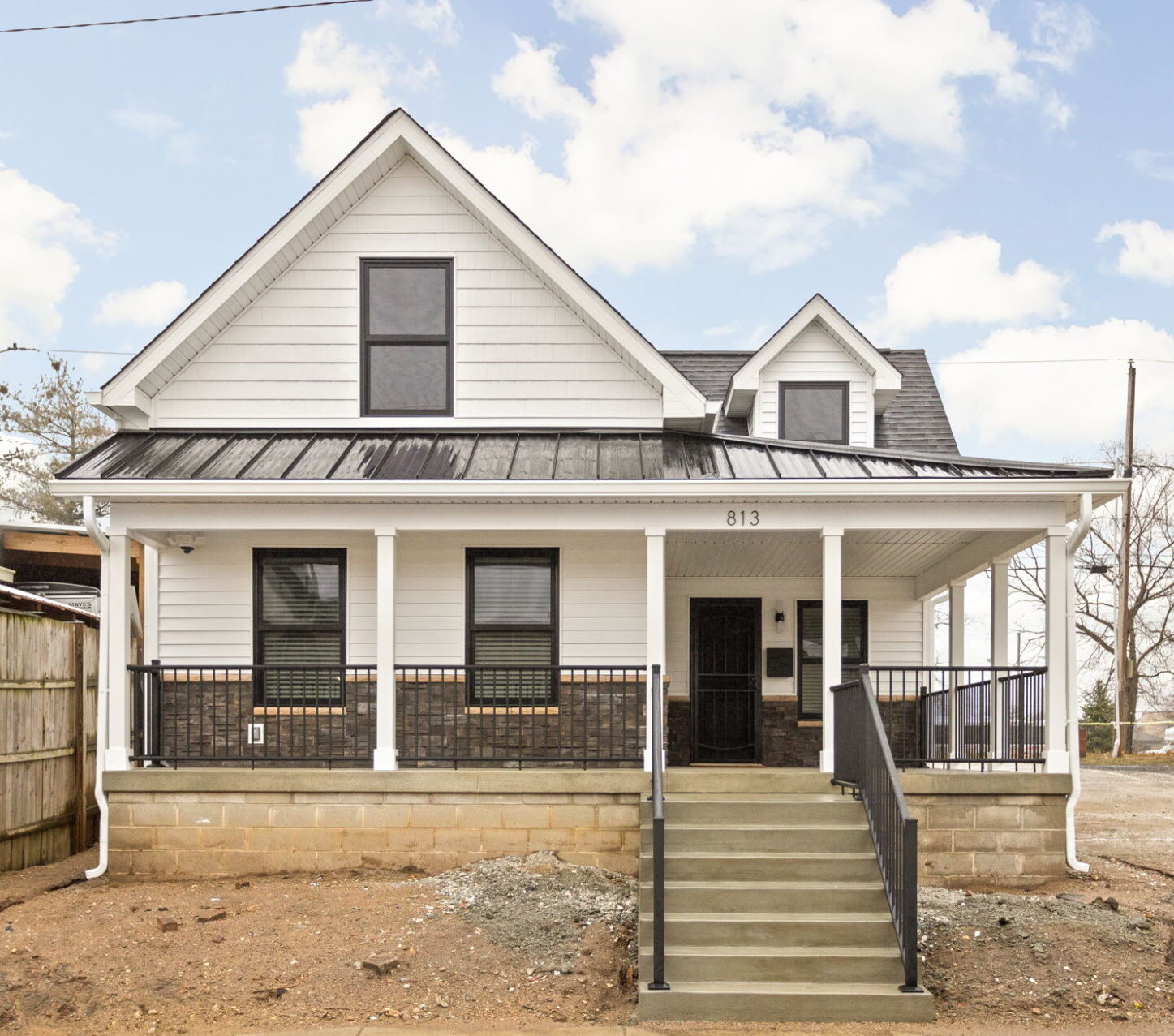 Renovated home exterior with white siding, black windows and a covered front porch