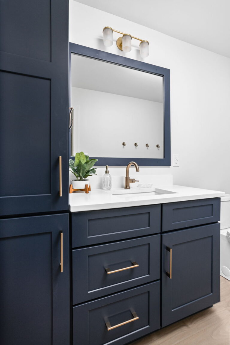 bathroom with blue cabinets and gold lighting