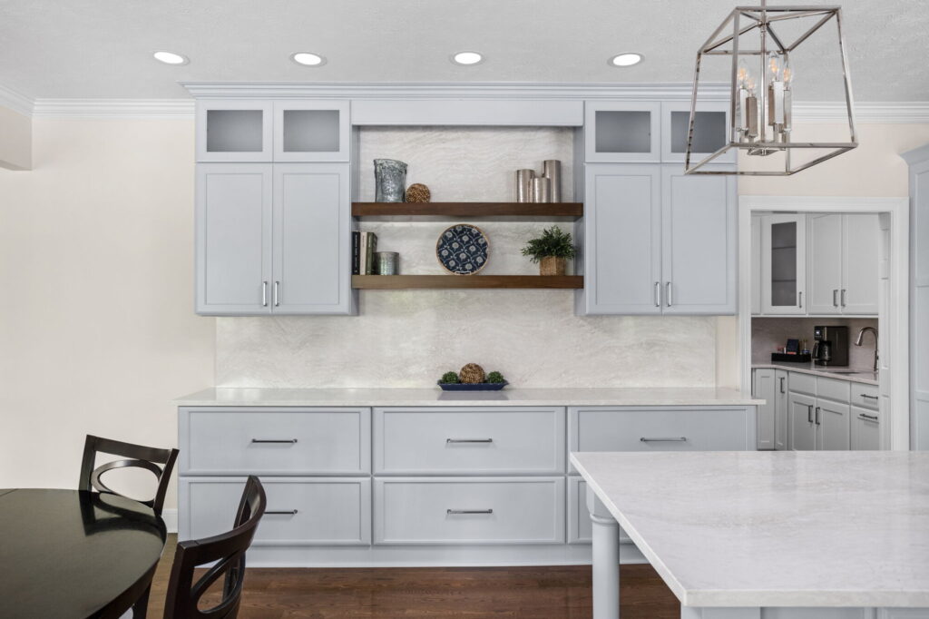 Carmel kitchen renovation refresh featuring refinished cabinetry, new buffet, bold tile, and timeless upgrades by Worthington Design & Remodeling. Photo shows buffet area. Light colored cabinetry with open wooden shelving connecting upper cabinets. Base cabinet is make up of three sets of drawers.