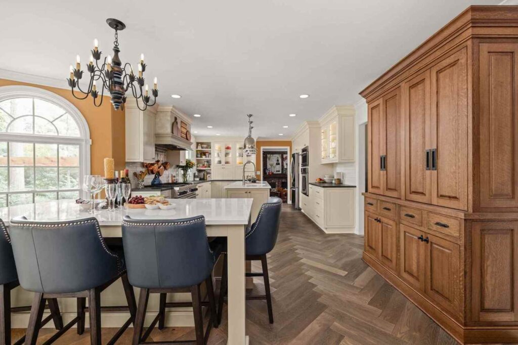 Open concept kitchen with seating island connecting to coffee and candy bar areas, arched windows, and herringbone floors.