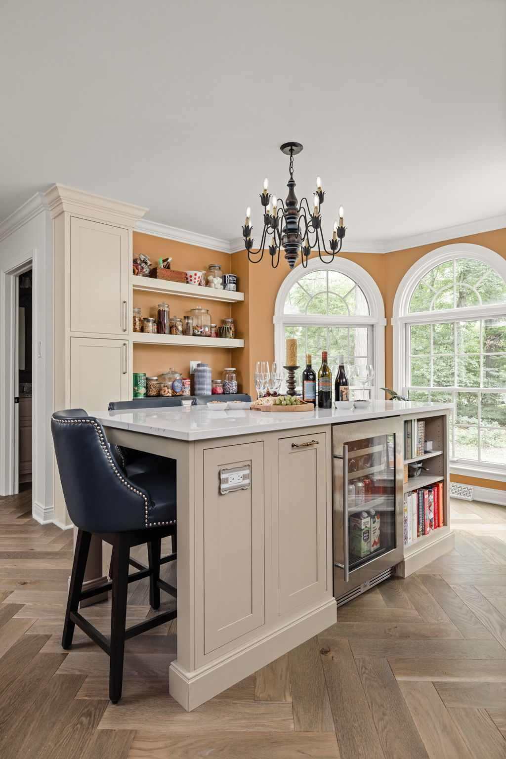 Seating island with beverage fridge and open shelving, bridging the kitchen to the coffee bar and candy bar.