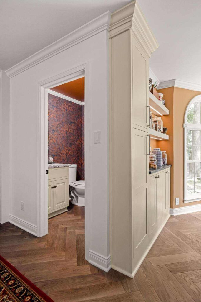 Hall view showing powder bath entrance and candy bar cabinetry integrated with the remodeled kitchen footprint.