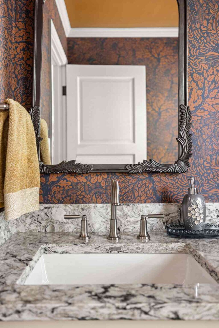 Powder bath sink and mirror detail with stone-look countertop and warm metal fixtures—part of a cohesive remodel.