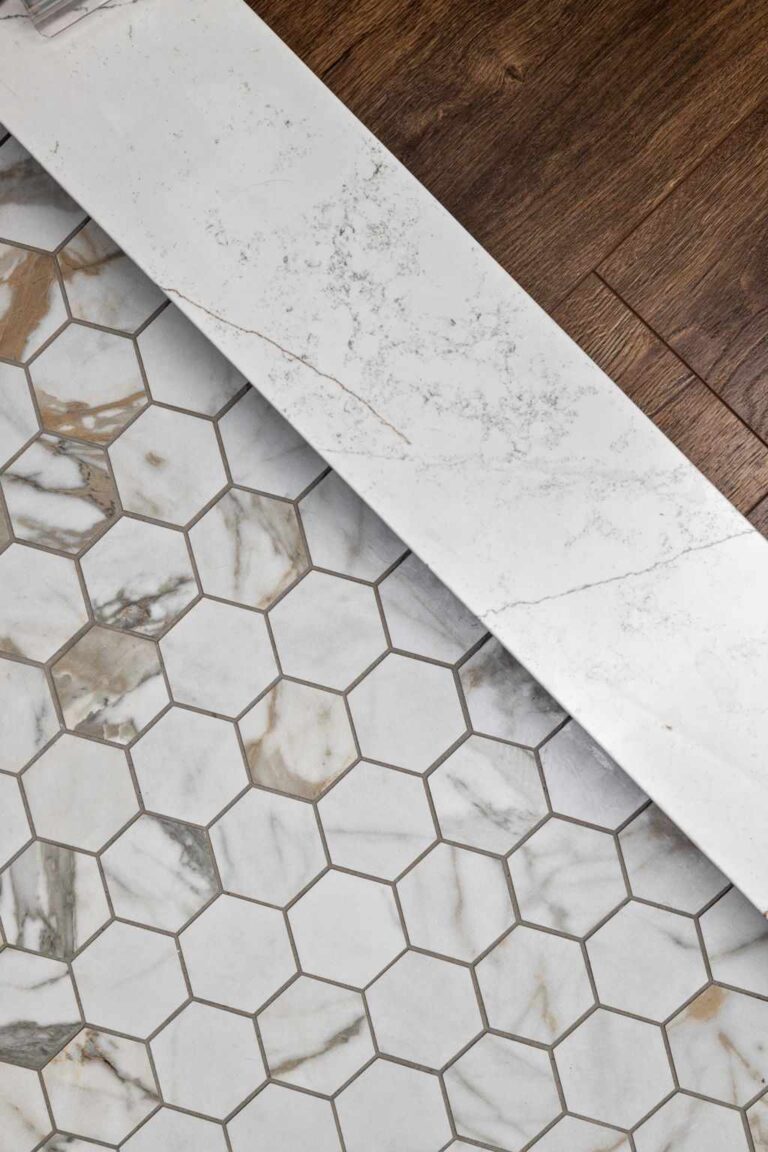 Detail of marble hexagon shower floor meeting white threshold and wood look flooring in a Zionsville IN main level bathroom remodel.