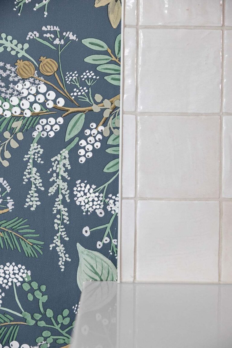 Transition detail showing floral wallpaper meeting white tile backsplash and quartz countertop in a custom kitchen refresh.