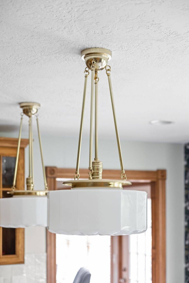 Brass pendant light with white glass shade hanging above the kitchen workspace in a refreshed oak cabinet kitchen.
