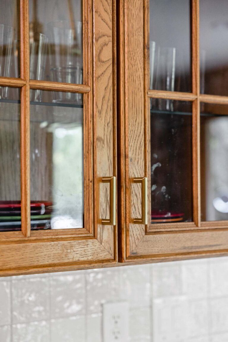 Glass front oak cabinet doors with brass pulls showcasing craftsmanship in a thoughtfully refreshed kitchen.