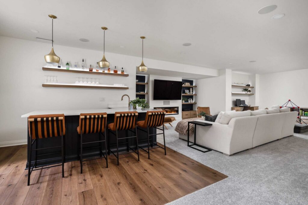 View of a finished Carmel basement showing the connection between the wet bar, seating area, and entertainment center for everyday living.