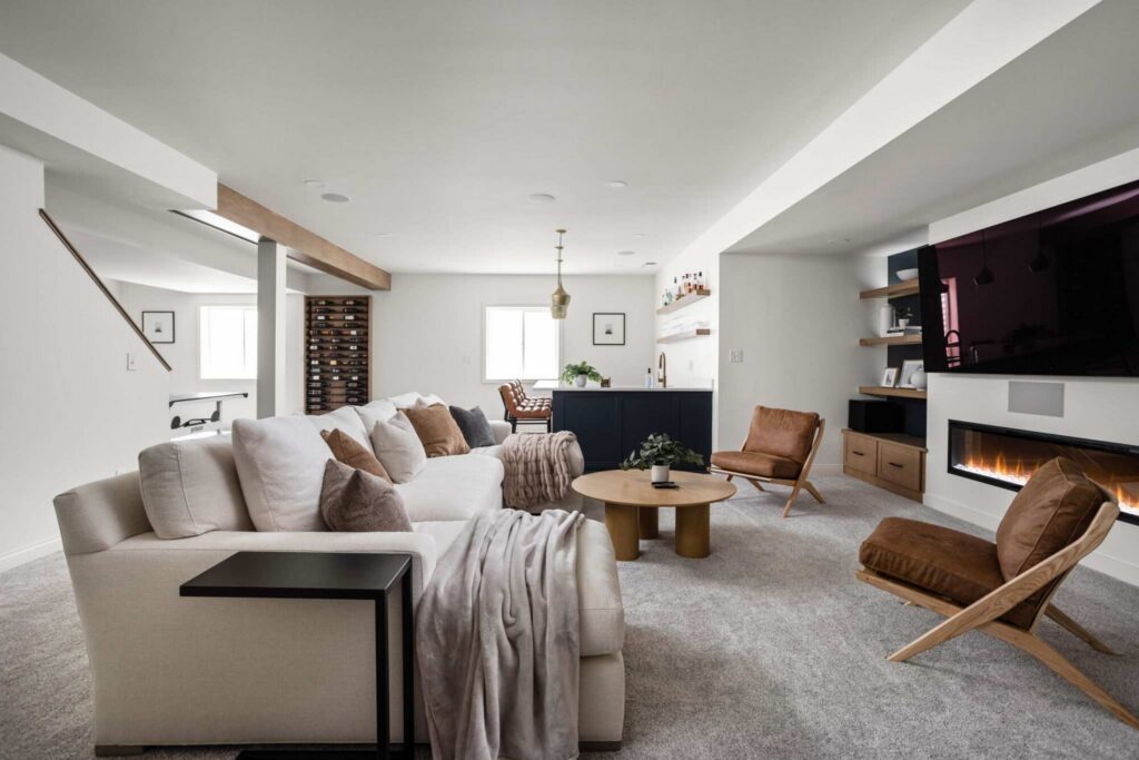 Open basement living area in Carmel Indiana with plush sectional seating, neutral finishes, and seamless flow between lounge and bar spaces.