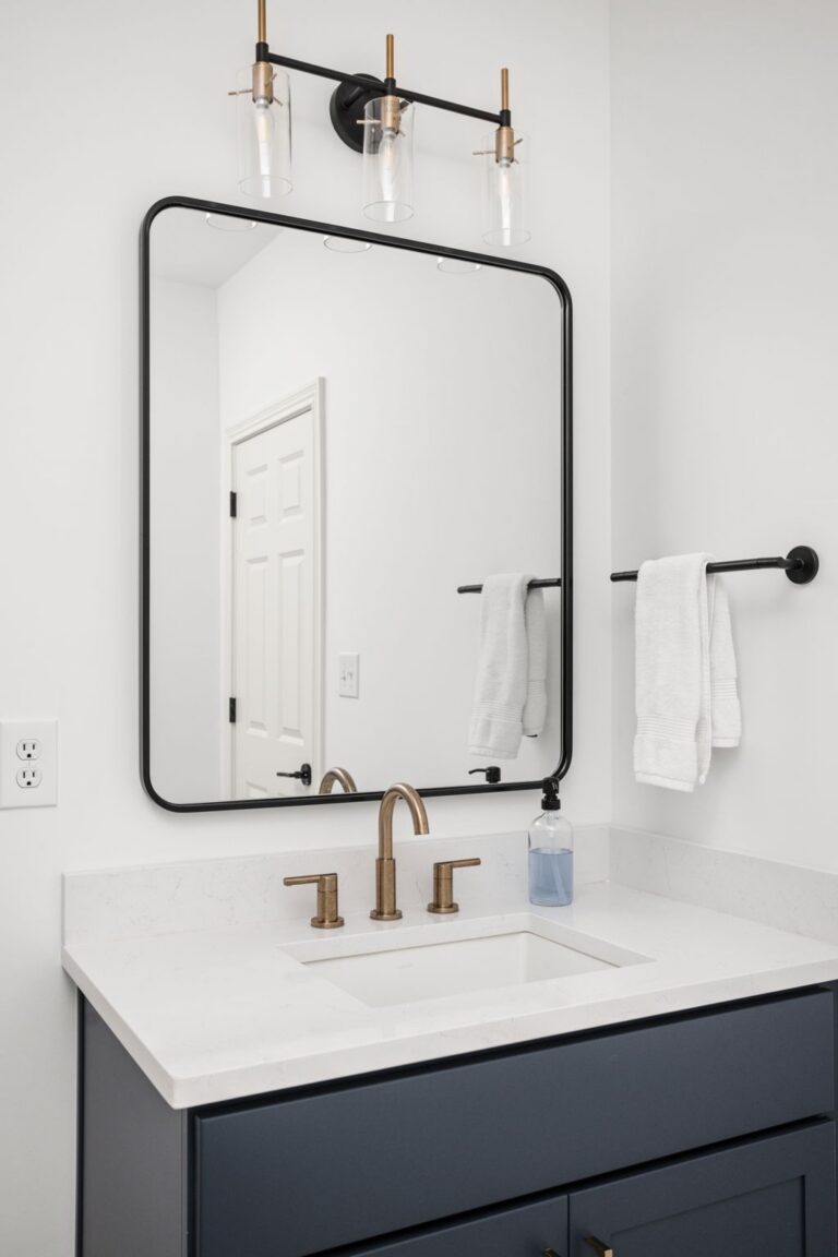 Custom basement bathroom vanity in Carmel IN with navy cabinetry, quartz countertop, and modern brass fixtures.