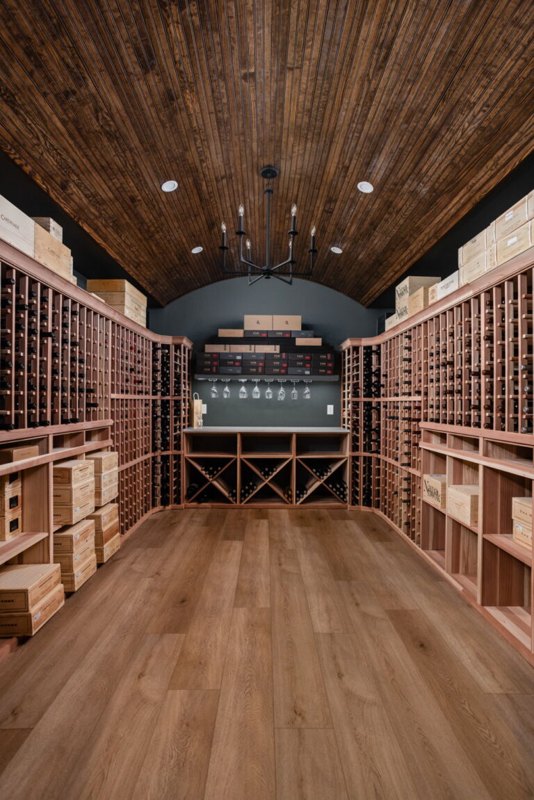 Custom wine cellar in a Carmel, Indiana basement remodel featuring built in wine racks, a quartz serving counter, accent lighting, and climate control planning by Worthington Design and Remodeling