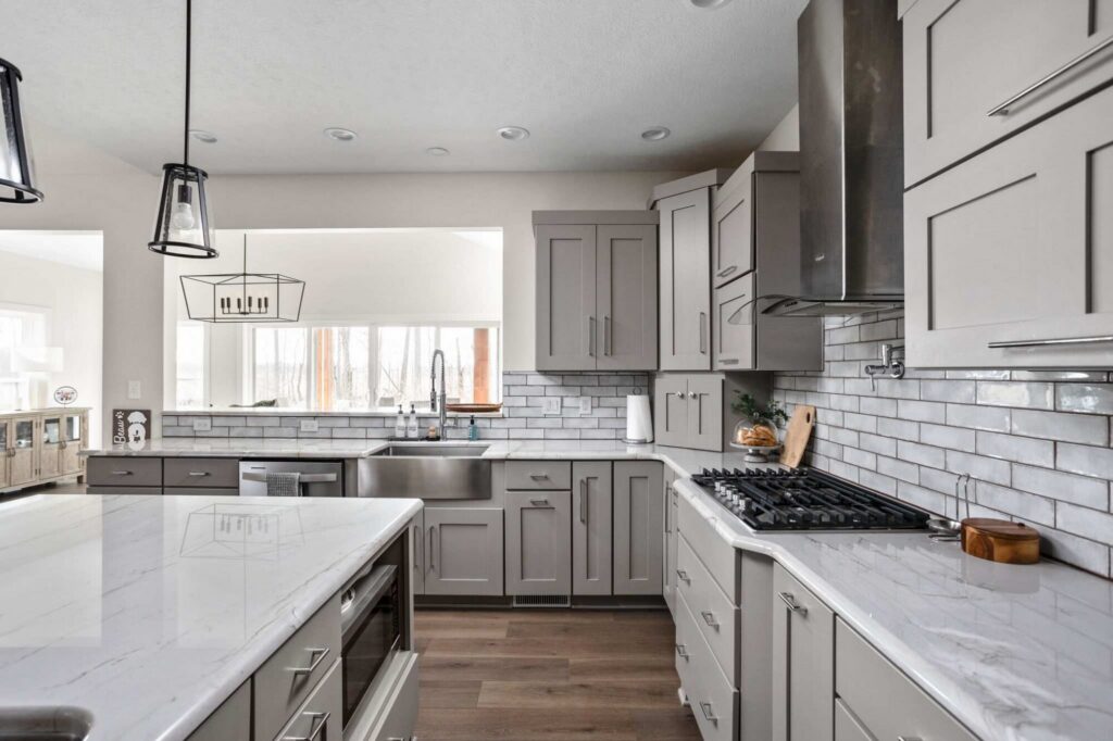 Kitchen corner with range wall and tile backsplash, showing refined cabinetry and countertop, four season room addition.