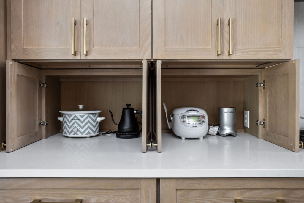 High end kitchen remodel Carmel showing an appliance garage with countertop storage for small kitchen appliances inside light wood cabinetry.