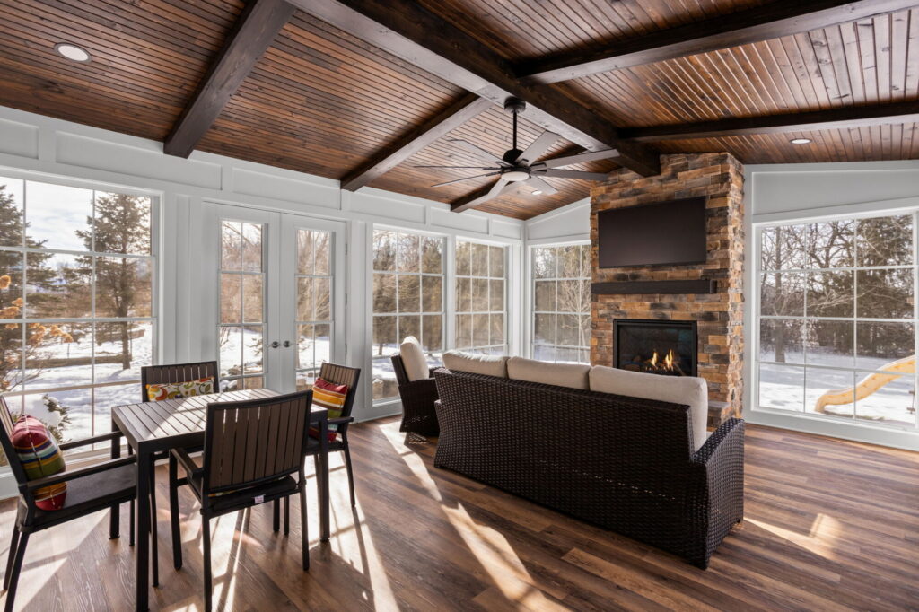 Wide interior of home addition remodel Carmel IN sunroom with dining area, fireplace, and patio doors.