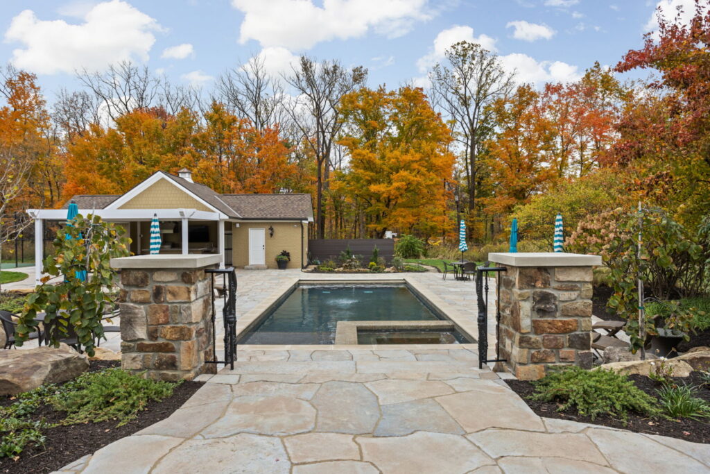Custom backyard pool and patio renovation with wide stone steps and views to the rear porch in Zionsville IN