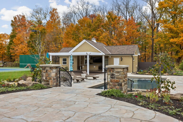 a pool house with a paver entry next to an inground pool