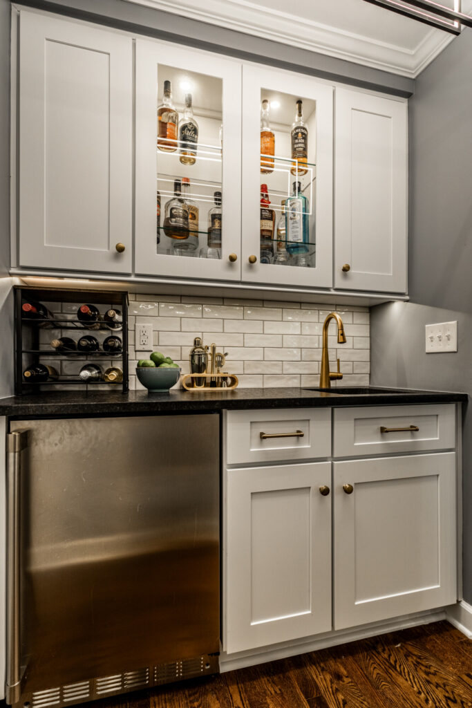 Wet bar in an Indianapolis remodel with custom cabinetry, countertop surface, backsplash tile, and integrated lighting