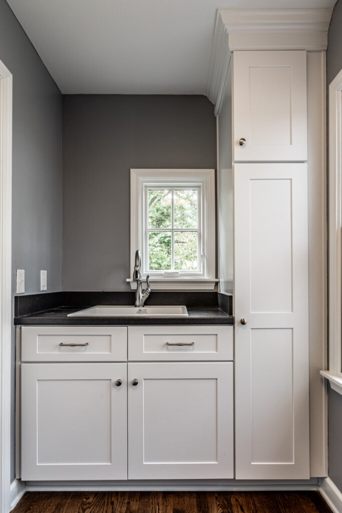 Laundry Room in an Indianapolis remodel with white cabinetry and contrasting black countertop surface.