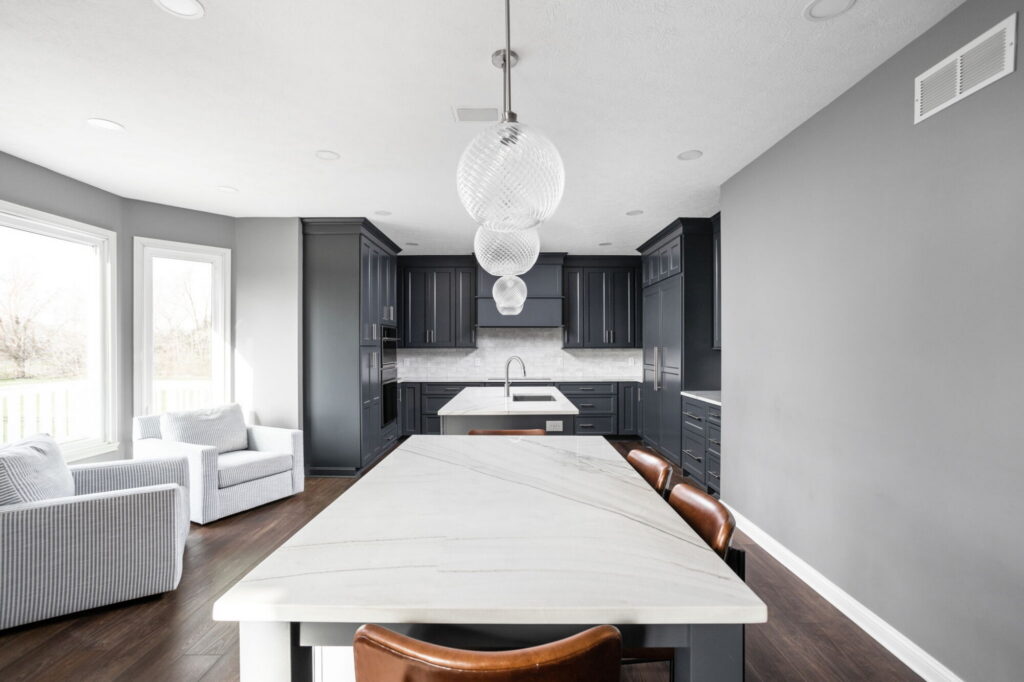 Wide view of the kitchen in this Fishers kitchen and bath remodel, featuring dark custom cabinetry, double islands, and large windows.