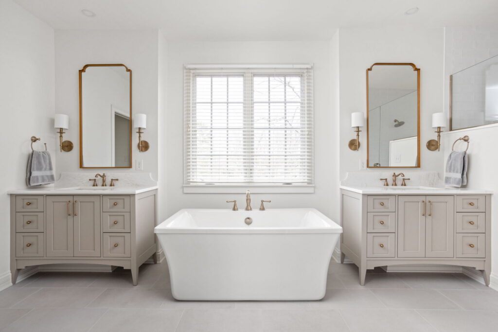 Primary bathroom with freestanding tub, double vanity in Amazing Gray, and brass fixtures in a luxury whole home remodeling project in Zionsville, Indiana