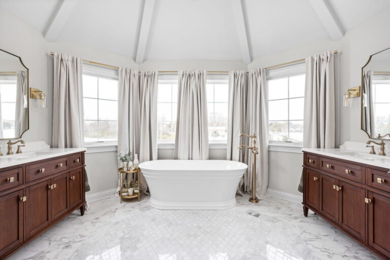 Primary bath remodel in Carmel IN with freestanding tub, dual wood vanities, marble floor tile, and vaulted ceiling
