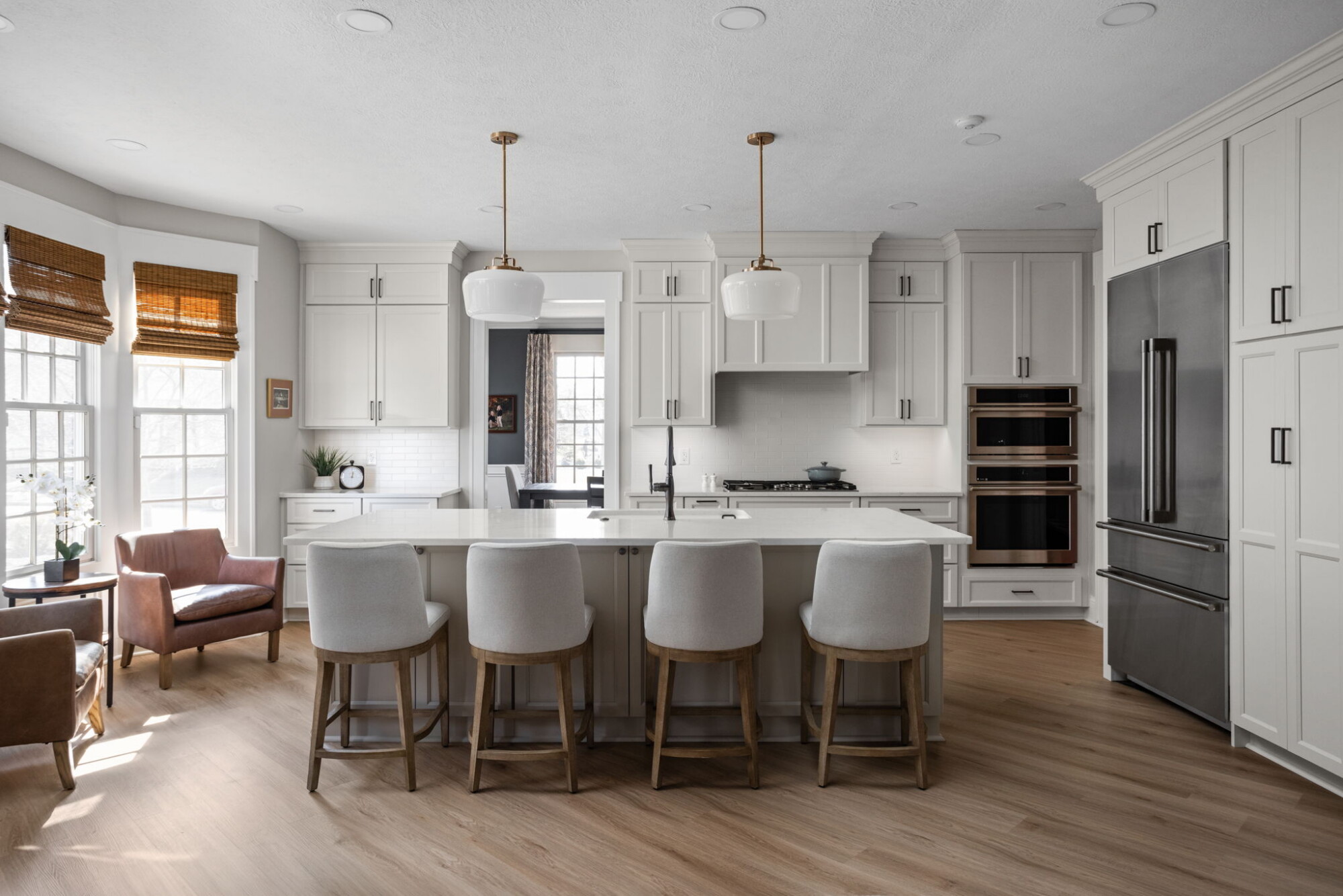 White kitchen with a large island, seating, cabinetry and integrated appliances