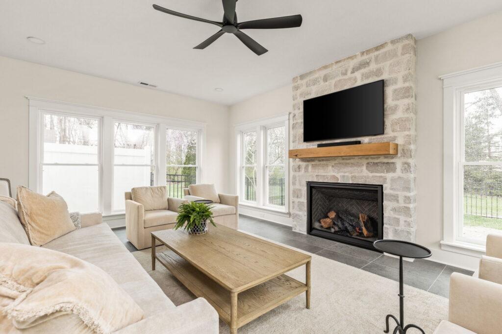Finished Carmel sunroom addition with a Halquist Stone fireplace, large windows, and luxury home addition details by Worthington Design & Remodeling.