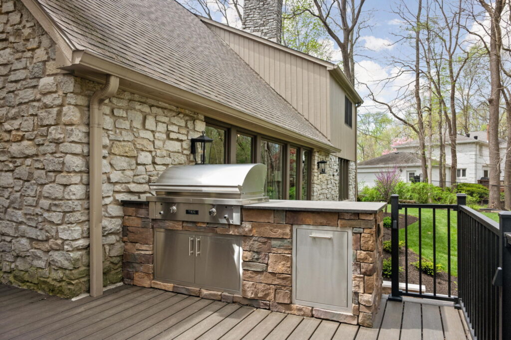 Carmel outdoor kitchen remodel with a stone grill island, stainless steel grill, Trex composite decking, and black aluminum railing.