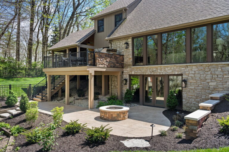 Carmel outdoor living remodel with elevated deck, outdoor kitchen, stamped concrete patio, circular gas firepit, and landscaped backyard.