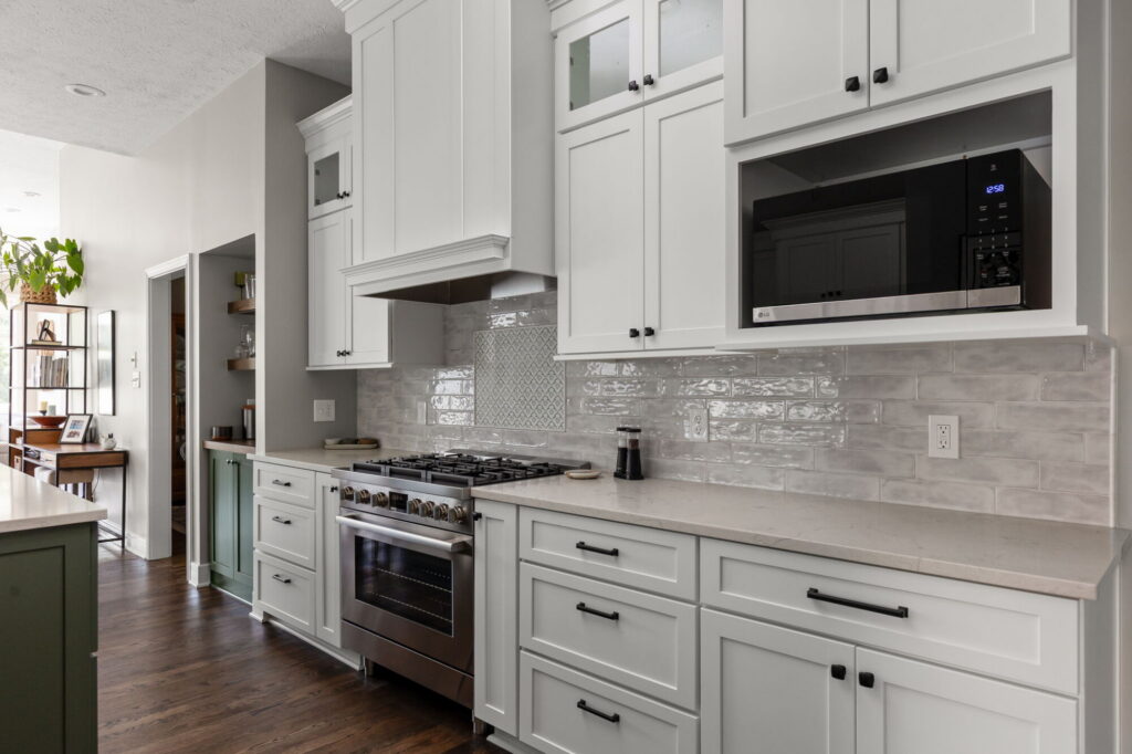 Finished Fishers kitchen range wall with a custom hood, stacked white cabinetry, Bosch range, and patterned tile accent.