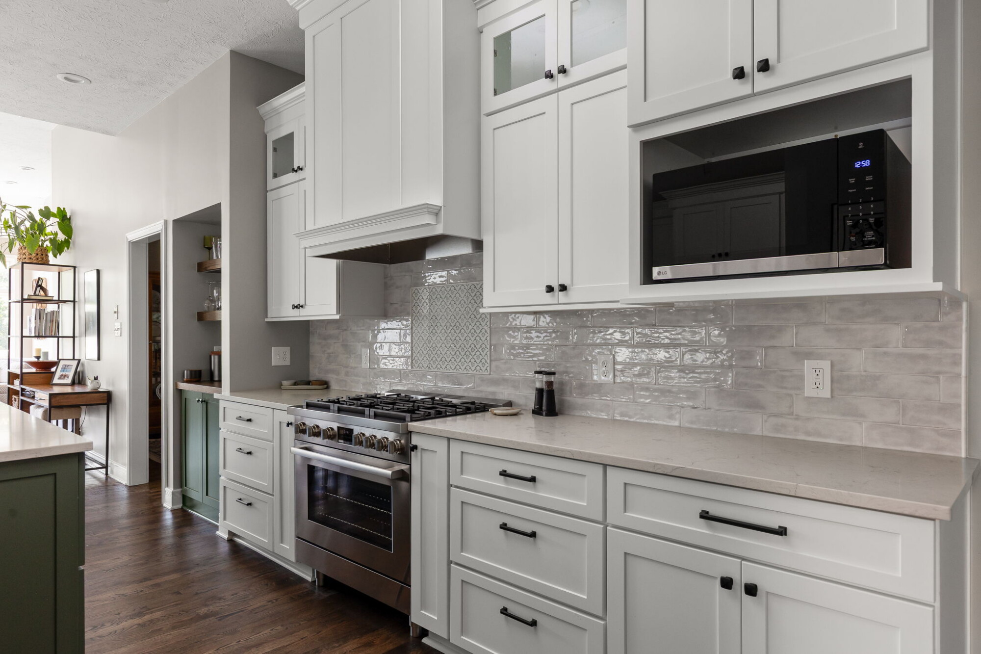 Finished Fishers kitchen range wall with a custom hood, stacked white cabinetry, Bosch range, and patterned tile accent.