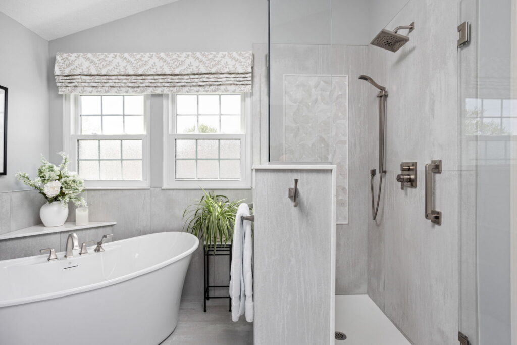 Finished primary bathroom layout in Fishers with freestanding tub, glass shower, window wall, and porcelain tile surround.