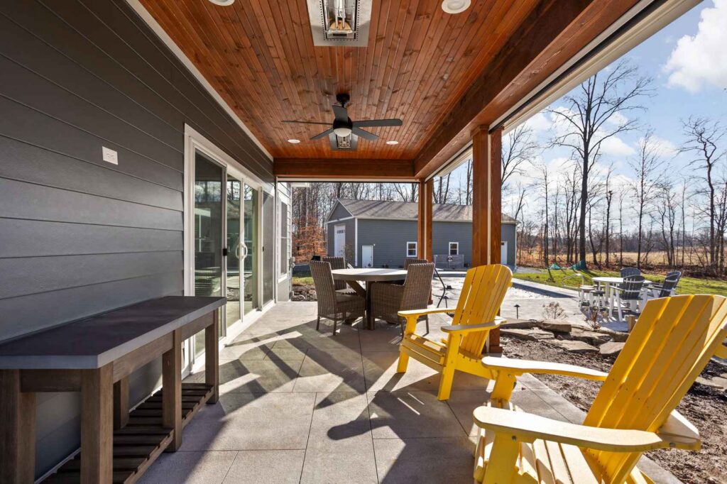Covered porch remodel in Indianapolis with cedar ceiling, wood columns, ceiling fan, and outdoor seating.