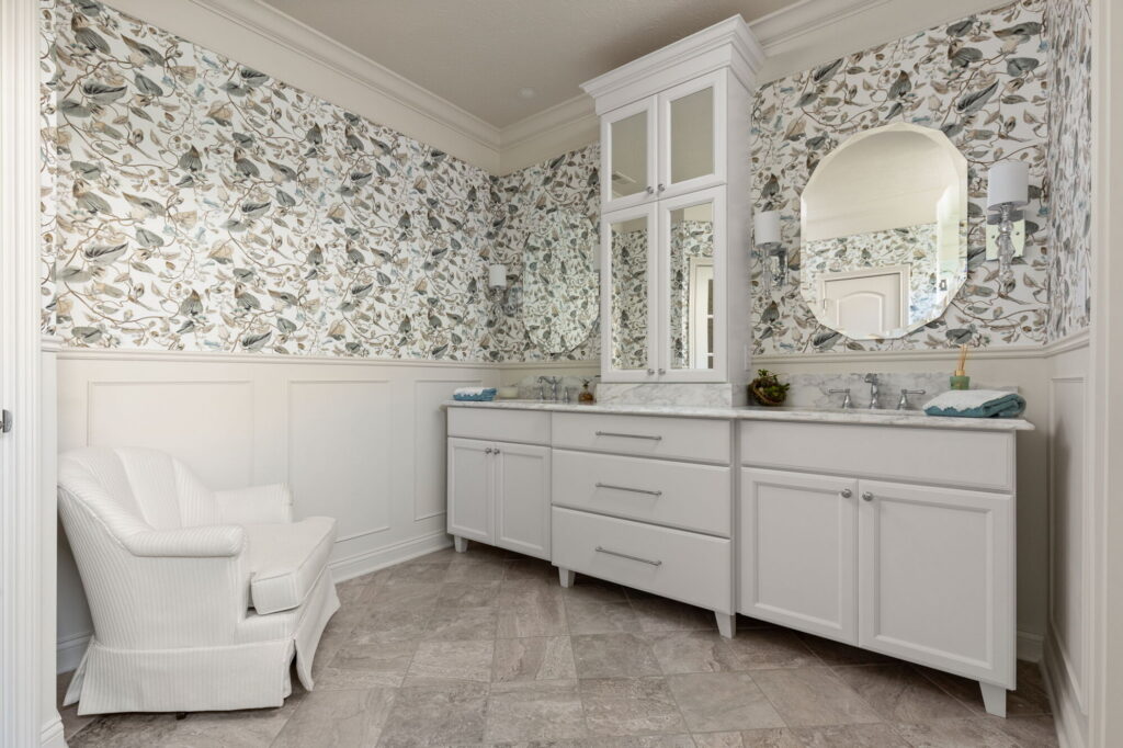 Westfield primary bathroom remodel with custom Shiloh vanity, painted wall paneling, floral wallpaper, and a small seating area.