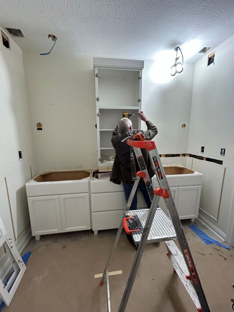 Shiloh bathroom vanity cabinetry being installed during a Westfield primary bathroom remodel with custom storage and a center wall cabinet.