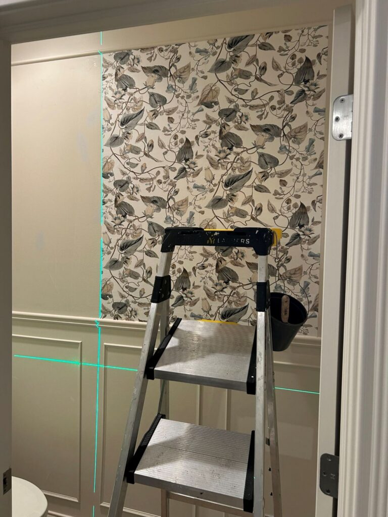 York Wallcoverings Moon Flower wallpaper being installed in a Westfield primary bathroom water closet above painted panel molding.