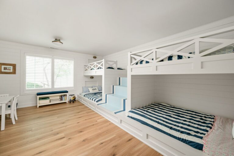 Bunkroom in the Nantucket Bay whole-house remodel with custom built-in beds, integrated stairs, shiplap walls and wood flooring.