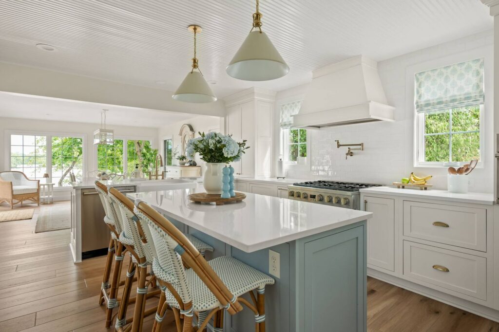 Kitchen in the Nantucket Bay whole-house remodel with blue island, Cambria quartz countertops, white cabinetry and beadboard ceiling.
