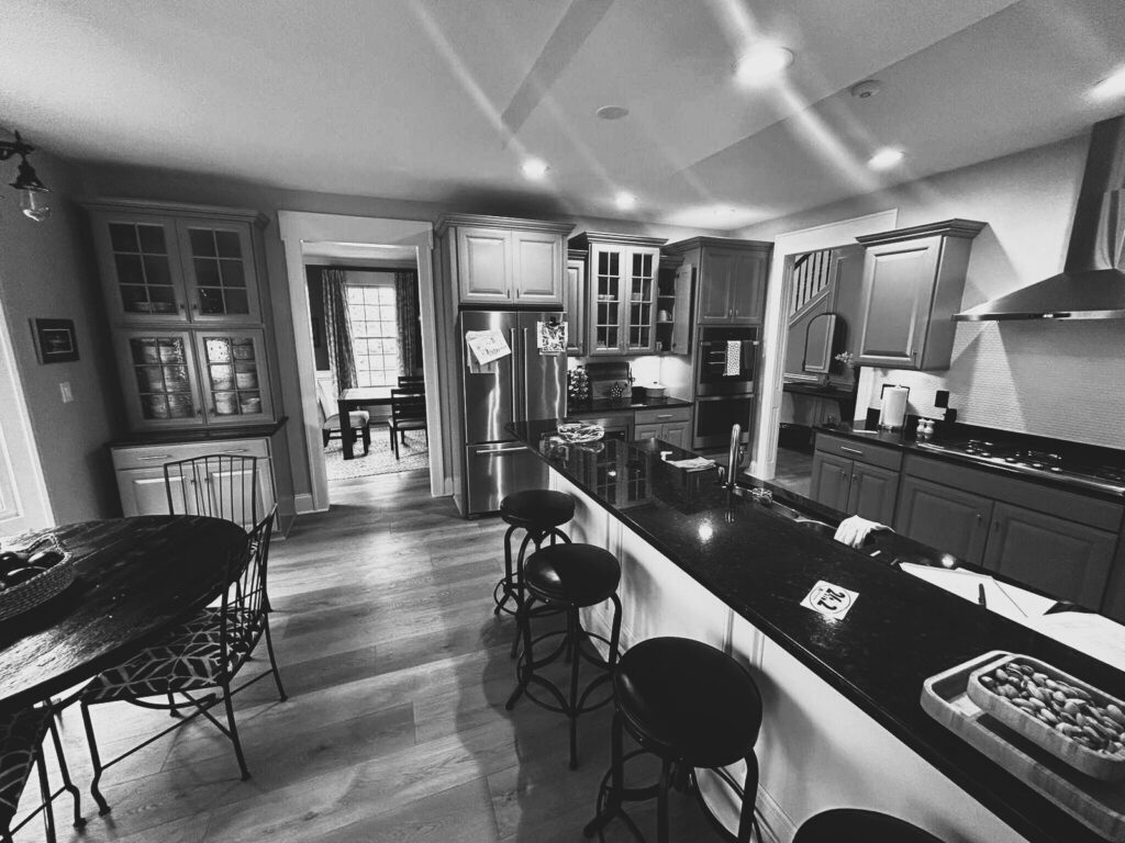 Before: West Clary kitchen with gray cabinetry, dark countertops and a long island beneath an overhead bulkhead.