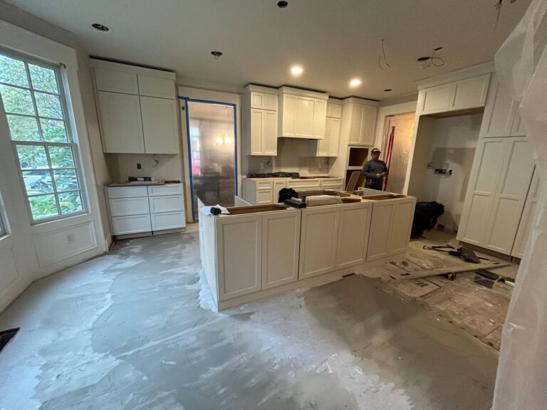 During construction: New white kitchen cabinetry and the island installed before countertops and finish work.