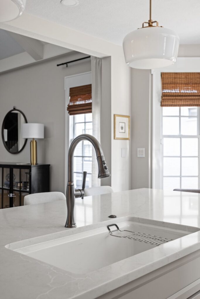 White undermount sink and pull-down faucet set into the quartz kitchen island.