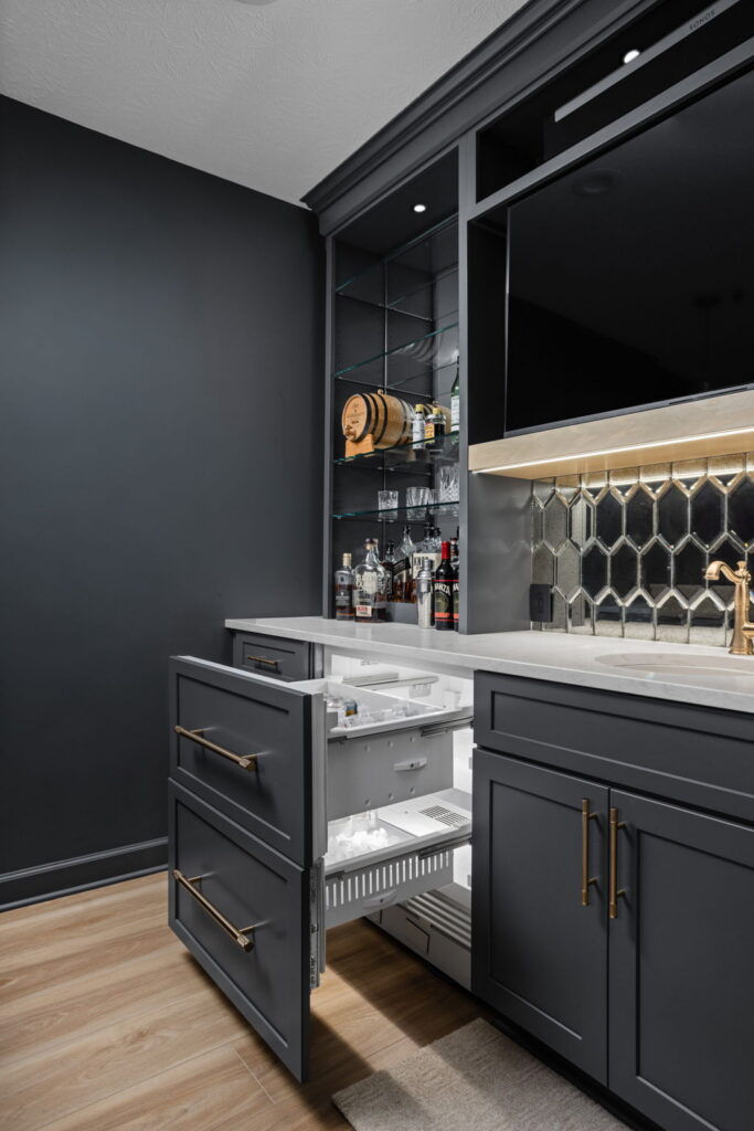 Open panel-front refrigerator and freezer drawers built into the wet bar beside the sink.