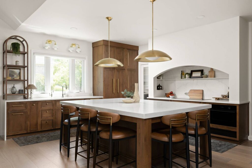 Carmel kitchen with an arched cooking alcove, quartz island, wood cabinets and seating on two sides.